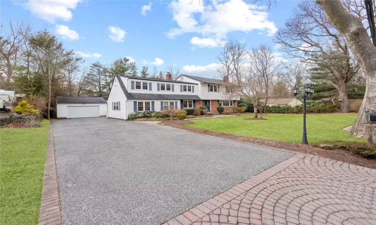 View of front of home featuring a front yard, a garage, and an outbuilding