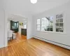 Unfurnished living room with baseboard heating, wood-type flooring, and crown molding