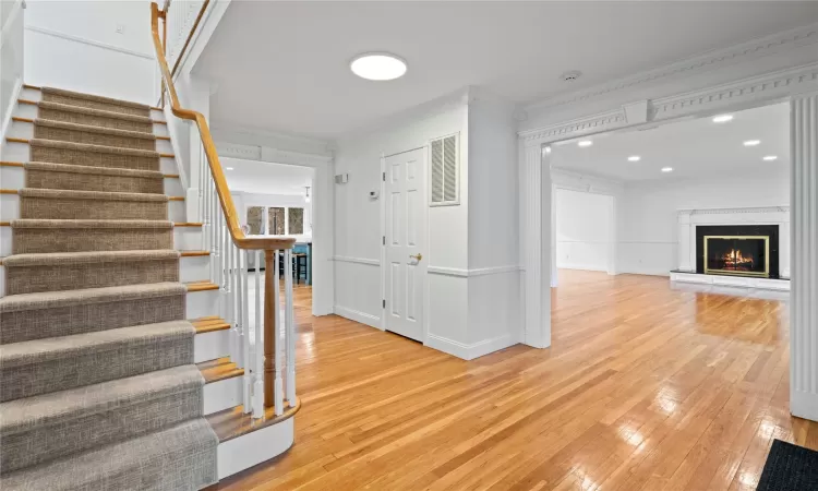 Stairway with hardwood / wood-style floors and ornamental molding