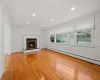 Unfurnished living room featuring a baseboard heating unit, a wealth of natural light, ornamental molding, and light hardwood / wood-style flooring