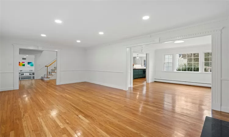 Unfurnished living room with light wood-type flooring, crown molding, and a baseboard radiator