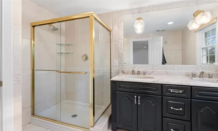 Bathroom featuring walk in shower, tile walls, and tasteful backsplash