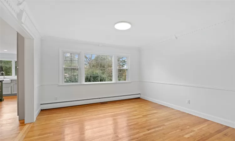 Spare room featuring baseboard heating, light hardwood / wood-style flooring, and crown molding