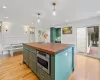 Kitchen with green cabinetry, hanging light fixtures, a center island, and wooden counters