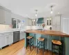 Kitchen with a kitchen bar, wooden counters, custom range hood, a kitchen island, and stainless steel dishwasher