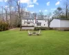 Back of house featuring a lawn, a wooden deck, and a fire pit