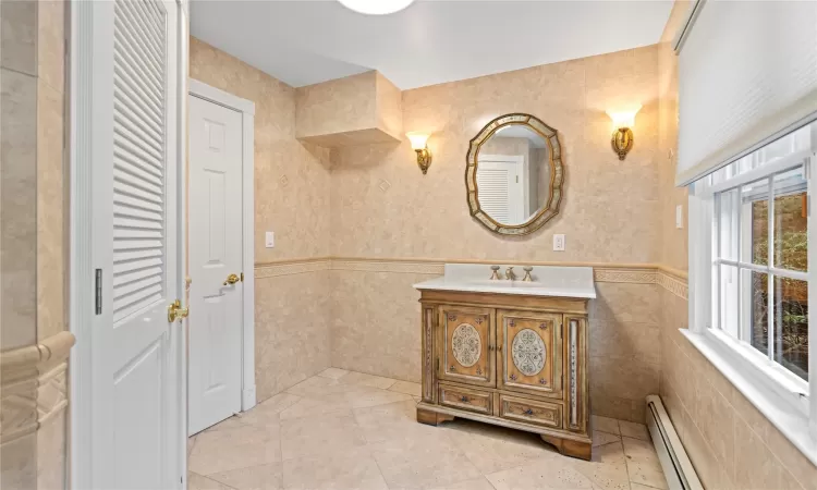 Bathroom with vanity, tile walls, tile patterned floors, and a baseboard radiator