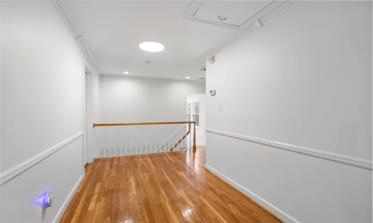 Hallway with crown molding and light hardwood / wood-style flooring