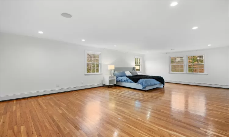 Unfurnished bedroom featuring a baseboard heating unit, crown molding, and light hardwood / wood-style floors