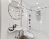 Full bathroom featuring bath / shower combo with glass door, tile walls, toilet, and sink