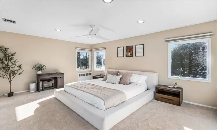 Carpeted bedroom featuring ceiling fan and radiator heating unit