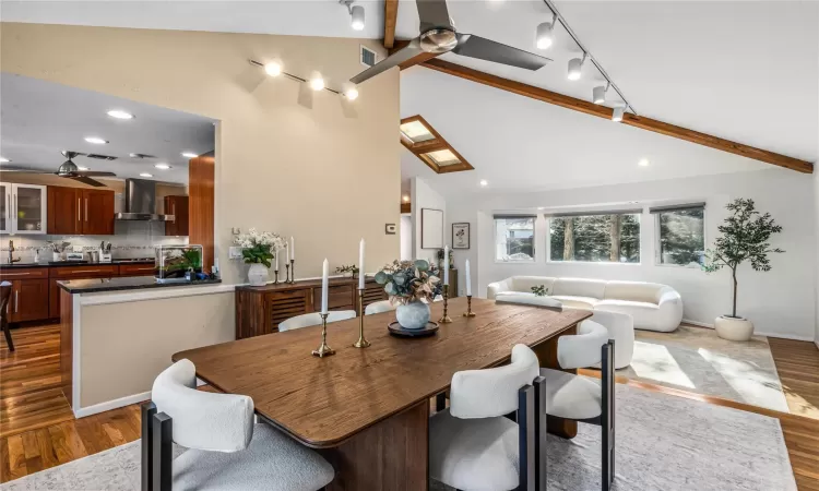 Dining room featuring ceiling fan, vaulted ceiling with skylight, and hardwood / wood-style floors