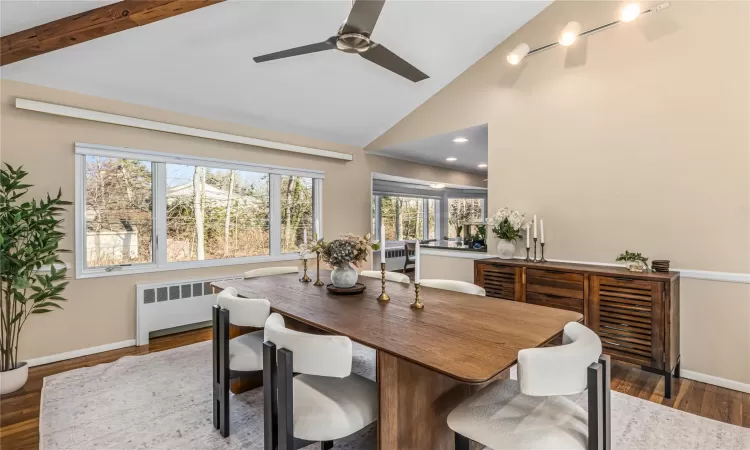 Dining room with ceiling fan, dark wood-type flooring, radiator, and high vaulted ceiling