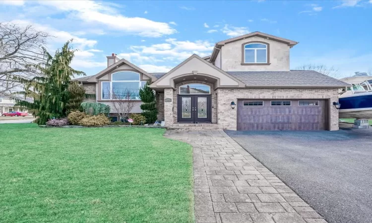 View of front of property featuring a garage, a front lawn, and french doors