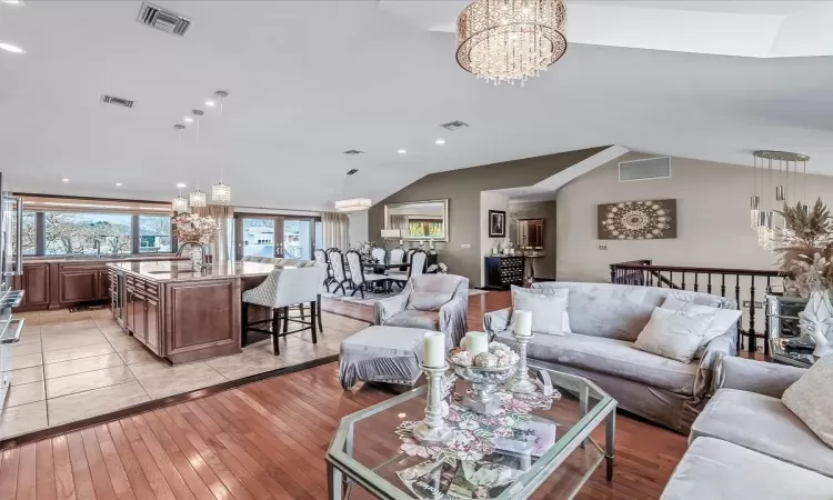 Dining area with vaulted ceiling, light wood-type flooring, and a notable chandelier