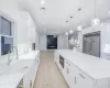 Kitchen featuring light stone countertops, decorative light fixtures, white cabinetry, stainless steel built in refrigerator, and decorative backsplash