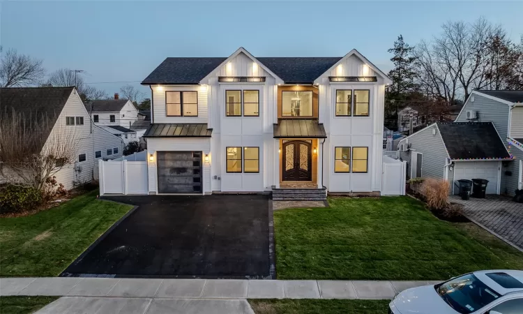 Modern farmhouse featuring a garage and a lawn