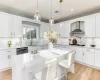 Kitchen with a center island, stainless steel dishwasher, white gas cooktop, white cabinets, and wall chimney exhaust hood