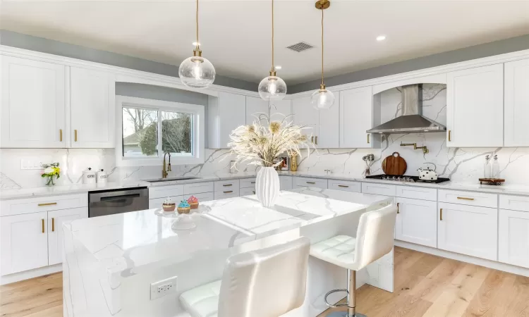 Kitchen with a center island, stainless steel dishwasher, white gas cooktop, white cabinets, and wall chimney exhaust hood