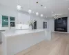 Kitchen with white cabinetry, tasteful backsplash, decorative light fixtures, light stone counters, and sink