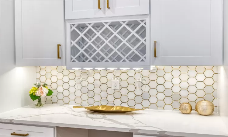 Details with tasteful backsplash, white cabinets, and light stone counters