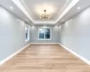 Unfurnished room featuring a raised ceiling, an inviting chandelier, and light hardwood / wood-style flooring