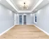 Spare room featuring light wood-type flooring, a notable chandelier, and a tray ceiling