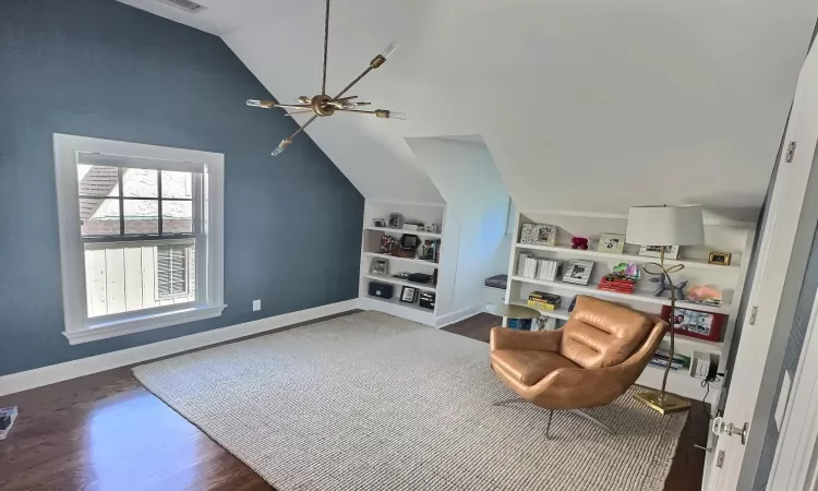 Living area with built in shelves, dark hardwood / wood-style floors, and lofted ceiling