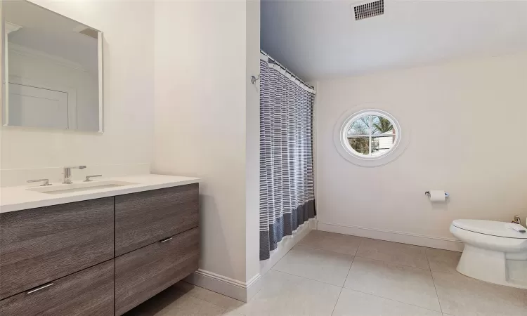 Bathroom featuring toilet, vanity, a shower with curtain, and tile patterned flooring