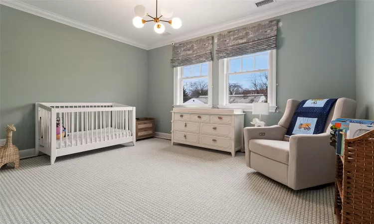 Carpeted bedroom featuring a nursery area, ornamental molding, and a chandelier