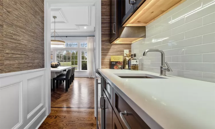 Kitchen featuring decorative light fixtures, dark brown cabinets, tasteful backsplash, and sink