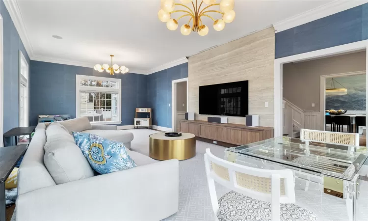 Living room with ornamental molding and a notable chandelier