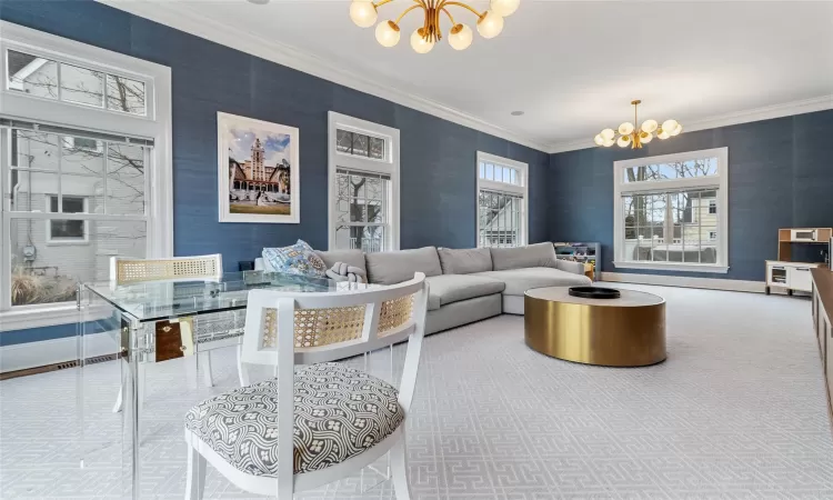 Living room featuring ornamental molding, a notable chandelier, and carpet flooring