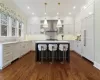 Kitchen with white cabinetry, a center island, dark hardwood / wood-style flooring, wall chimney range hood, and sink