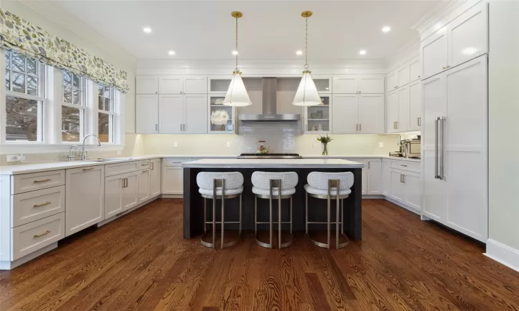 Kitchen with white cabinetry, a center island, dark hardwood / wood-style flooring, wall chimney range hood, and sink