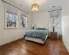 Bedroom with dark hardwood / wood-style floors, crown molding, and an inviting chandelier