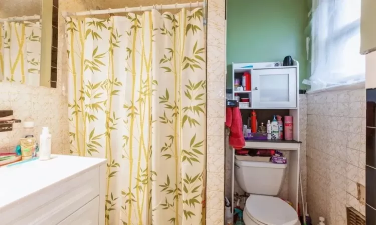 Bathroom with toilet, a shower with curtain, and vanity