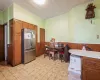 Kitchen with ornamental molding, tile countertops, wood walls, and stainless steel refrigerator