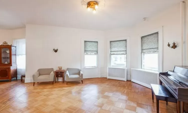 Sitting room featuring radiator heating unit and light parquet floors