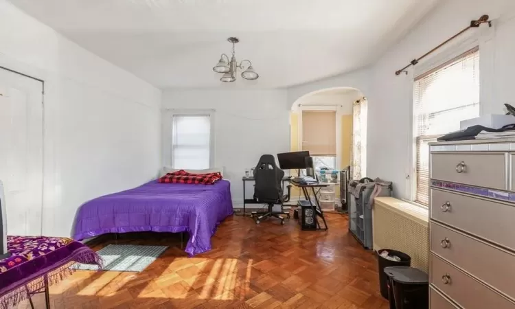 Bedroom with a chandelier and dark parquet floors