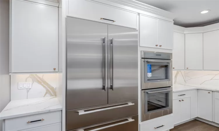 Kitchen featuring appliances with stainless steel finishes, dark hardwood / wood-style flooring, white cabinetry, and light stone countertops