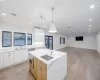 Kitchen featuring sink, a center island with sink, white cabinets, and light stone counters