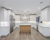 Kitchen with white cabinetry, pendant lighting, stainless steel appliances, and a center island with sink