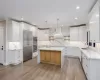 Kitchen featuring white cabinetry, sink, hanging light fixtures, and a kitchen island with sink