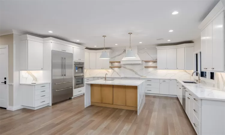 Kitchen featuring white cabinetry, sink, hanging light fixtures, and a kitchen island with sink