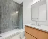 Bathroom featuring toilet, vanity, and tiled shower