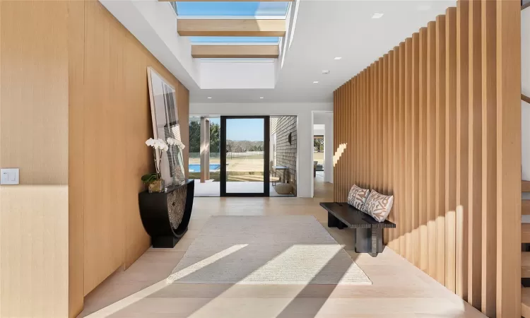 Hallway featuring wood walls, light hardwood / wood-style floors, and a skylight