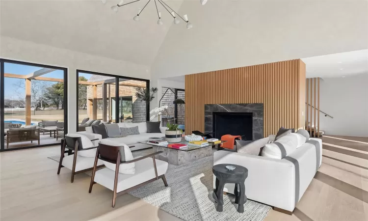 Living room featuring high vaulted ceiling, a notable chandelier, a tile fireplace, and light hardwood / wood-style floors