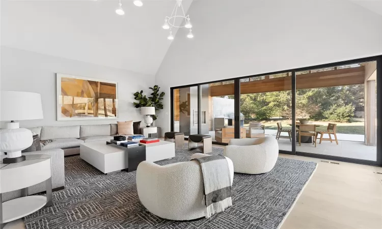 Living room with an inviting chandelier, dark hardwood / wood-style floors, and high vaulted ceiling