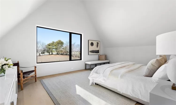 Bedroom with vaulted ceiling and light hardwood / wood-style floors